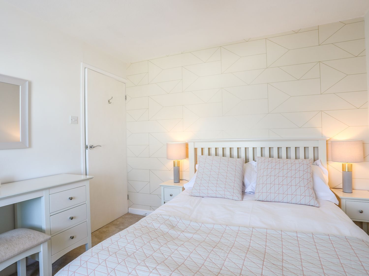 A bedroom with a bed, bedside tables, a dresser, and a mirror.