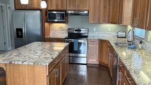 Uma cozinha moderna com armários de madeira, eletrodomésticos de aço inoxidável, bancadas de granito e uma ilha grande.