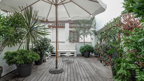 A wooden deck with a white umbrella, potted plants, and a white bench. - Beach Villa Aralinn by Hello Homes Sitges (Sitges)