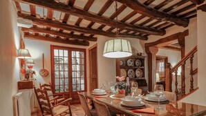 A dining area with a glass table, wicker chairs, a wooden ceiling, and a view through a window. - Beach Villa Aralinn by Hello Homes Sitges (Sitges)
