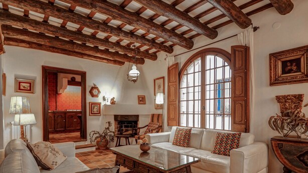 A cozy living room with a fireplace, white sofas, and a large arched window. - Beach Villa Aralinn by Hello Homes Sitges (Sitges)
