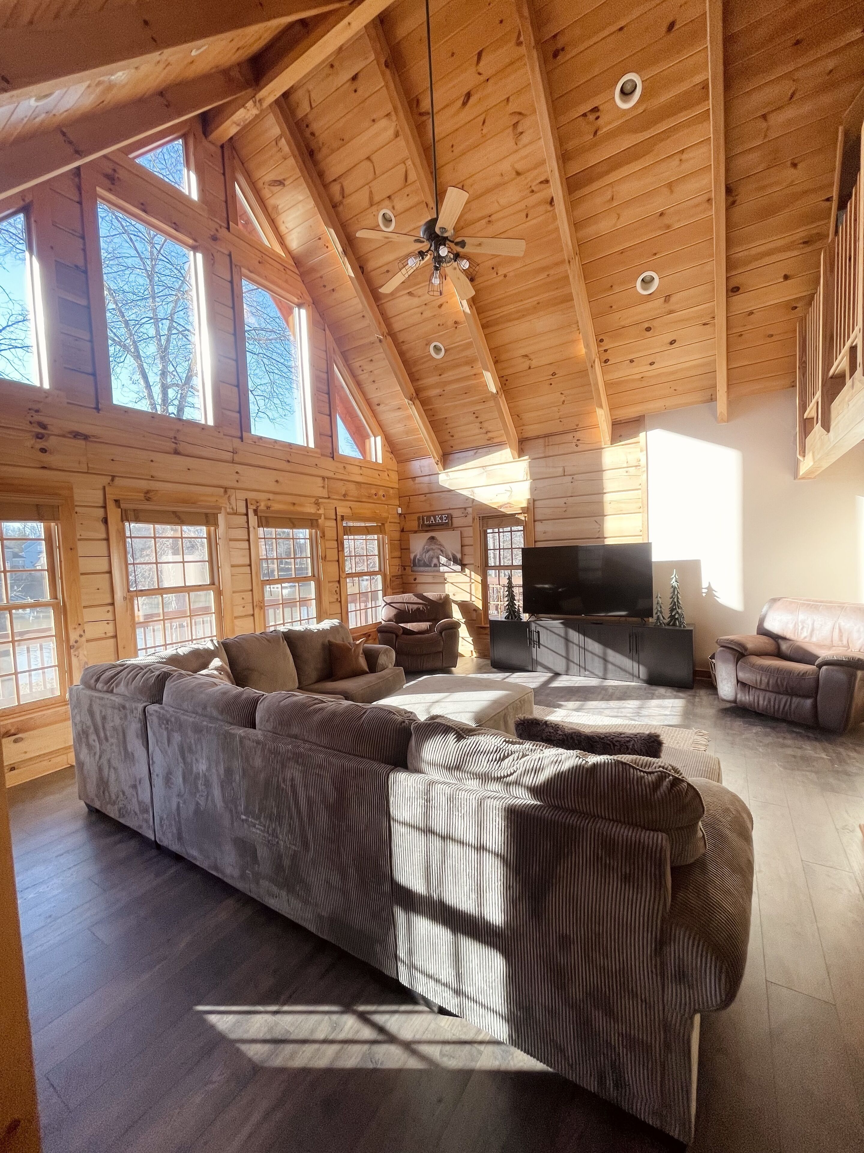 A spacious living room with a large sectional sofa, a flat-screen TV, and a fireplace.