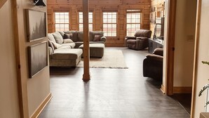 A cozy log cabin interior with a sectional sofa, a recliner, and a rug.