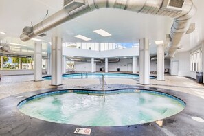 Relax by the pool, surrounded by a tiled deck and multiple columns, with a hot tub at its center.