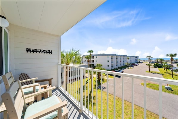 Enjoy the view from this hotel room's balcony overlooking the parking area and nearby building.