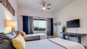 A hotel room with two beds, a desk with a chair, a television, and a ceiling fan. - Unit 22 Waena Inn - Maui Private Suite (Wailuku)