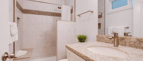 A modern bathroom with a shower, toilet, and sink.