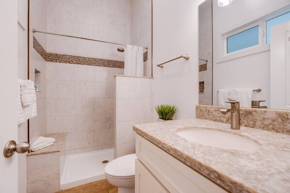 A modern bathroom with a shower, toilet, and sink.