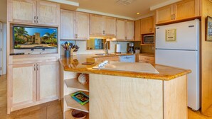 Una cocina moderna con armarios de madera, microondas integrado, refrigerador y una isla grande con pileta.