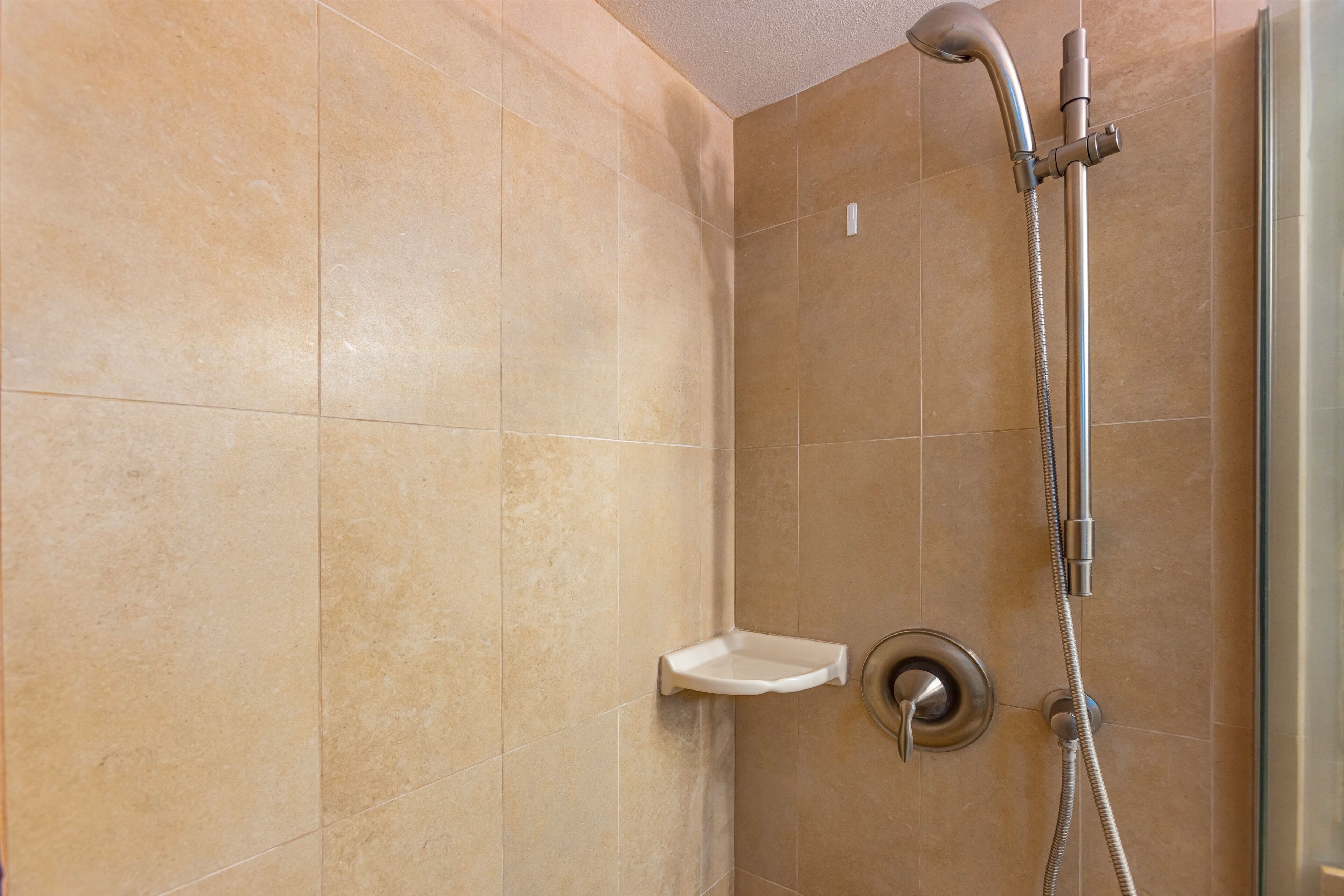 Ein Duschbereich mit Handbrause und am Wand montierter Armatur.
