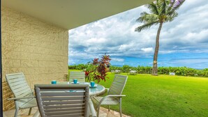 Un patio con una mesa y sillas, vista a un área verde y una palmera.
