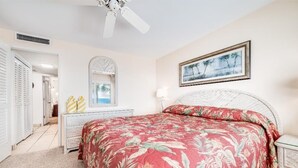 A bedroom with a bed, a ceiling fan, a dresser, a mirror, and a framed picture on the wall. - Kihei Beach, #409 2 Bedroom Condo by RedAwning (Kihei)