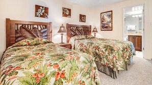 A bedroom with two beds, a ceiling fan, and artwork on the walls.