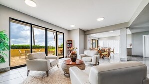 A spacious living area with a large window, a dining table, and comfortable seating.
