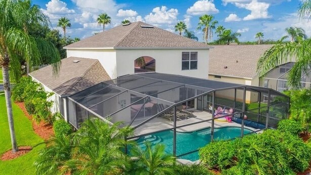Ein Haus mit Swimmingpool, überdachter Terrasse und weißer Fassade.