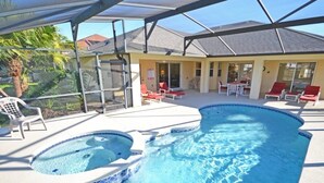 A swimming pool with a hot tub, lounge chairs, and a covered patio area.