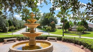 A multi-tiered stone fountain in a landscaped garden with benches and a sign reading "COUNTRYVIEW."