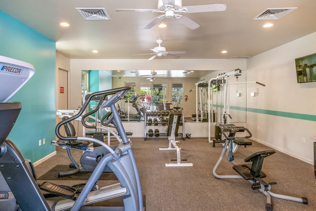 Ein Fitnessstudio mit Laufbändern, Crosstrainern und Gewichten.