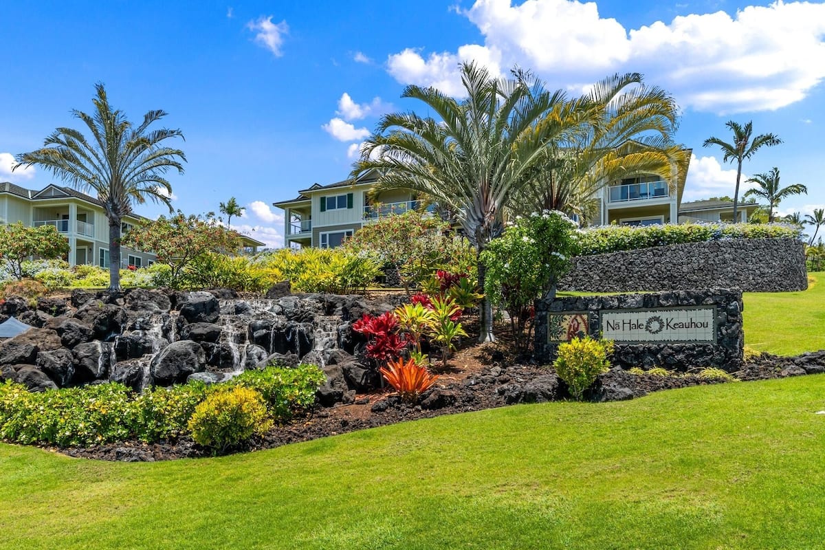 A landscaped area with a stone wall, a small waterfall, and a sign reading "Na Hale Keauhou".