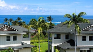 A coastal residential area with houses featuring gabled roofs and white exteriors, surrounded by lush greenery and palm trees, with the ocean in the background. - Big Island Na Hale O Keauhou by Coldwell Banker Island Vacations (Kailua-Kona)