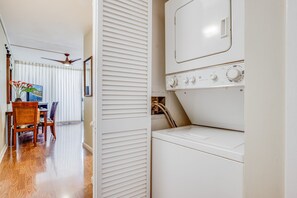 A laundry room with a front-loading washer and dryer, a ceiling fan, and a dining area with a table and chairs. - Sugar Beach Resort, #418 1 Bedroom Condo by RedAwning (Kihei)