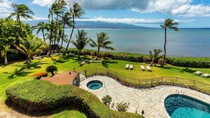 A pool area with a hot tub, lounge chairs, and a view of the ocean.