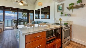 A modern kitchen with a large island, built-in oven, and a view to the outside.