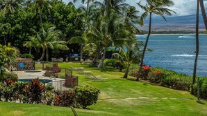 A tropical resort with a pool, lounge chairs, and palm trees overlooking the ocean.