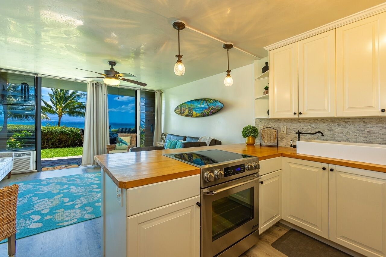 A modern kitchen with a large island, built-in oven, and white cabinetry.