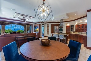 Uma sala de jantar espaçosa com uma mesa de madeira redonda, cadeiras azuis e um centro de mesa decorativo.