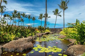 A tropical resort with a water feature, palm trees, and a view of the ocean. - Wailea Beach Villas by Coldwell Banker Island Vacations (Kihei)