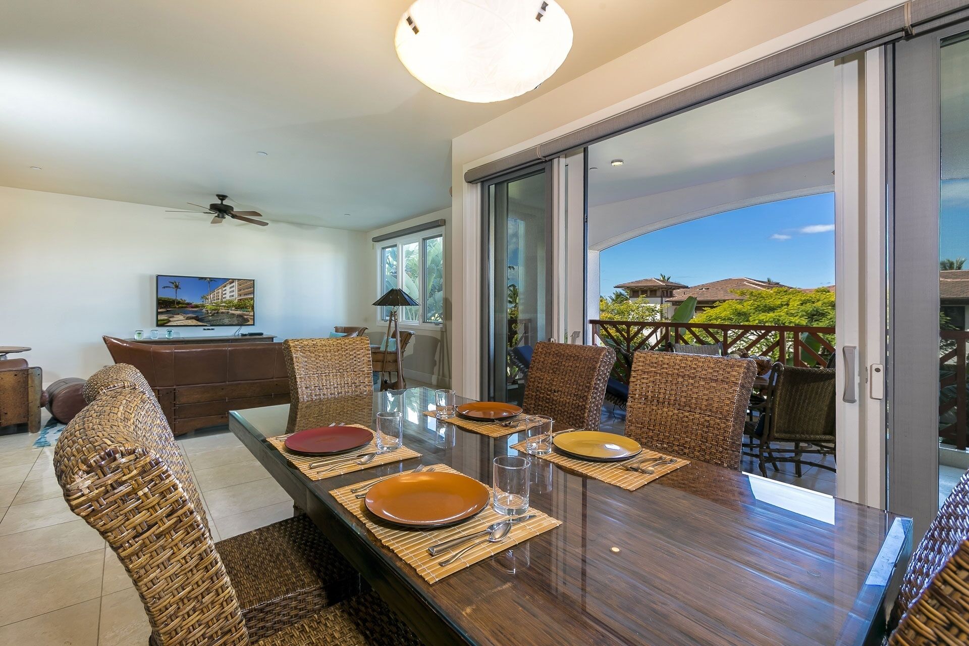 A dining area with a glass table, wicker chairs, and a view of the outdoors.