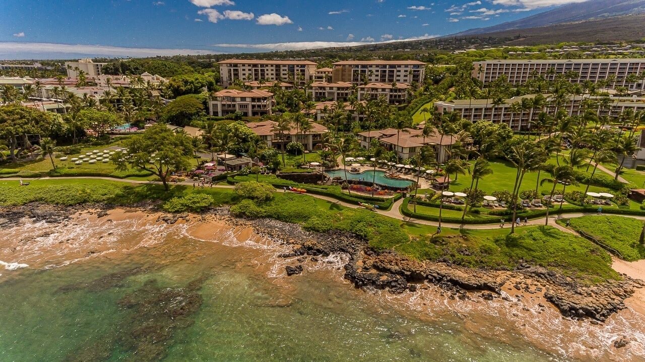 A resort with multiple buildings, a beachfront, and a pool area.