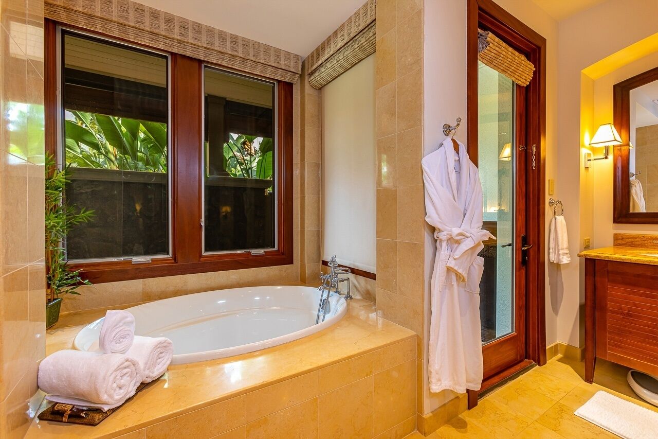 A modern bathroom with a large bathtub, a glass shower enclosure, and a wooden vanity.