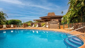 A clear blue swimming pool with lounge chairs and a stone wall. - Kaanapali Plantation by Coldwell Banker Island Vacations (Lahaina)