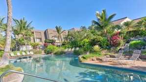A swimming pool with lounge chairs, palm trees, and a building in the background. - Maui Kamaole by Coldwell Banker Island Vacations (Kihei)