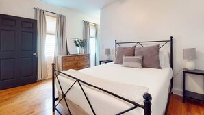 Un dormitorio con cama, ventilador de techo, cómoda y mesita de noche.