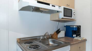 Cocina compacta equipada con estufa, fregadero, microondas y cafetera.
