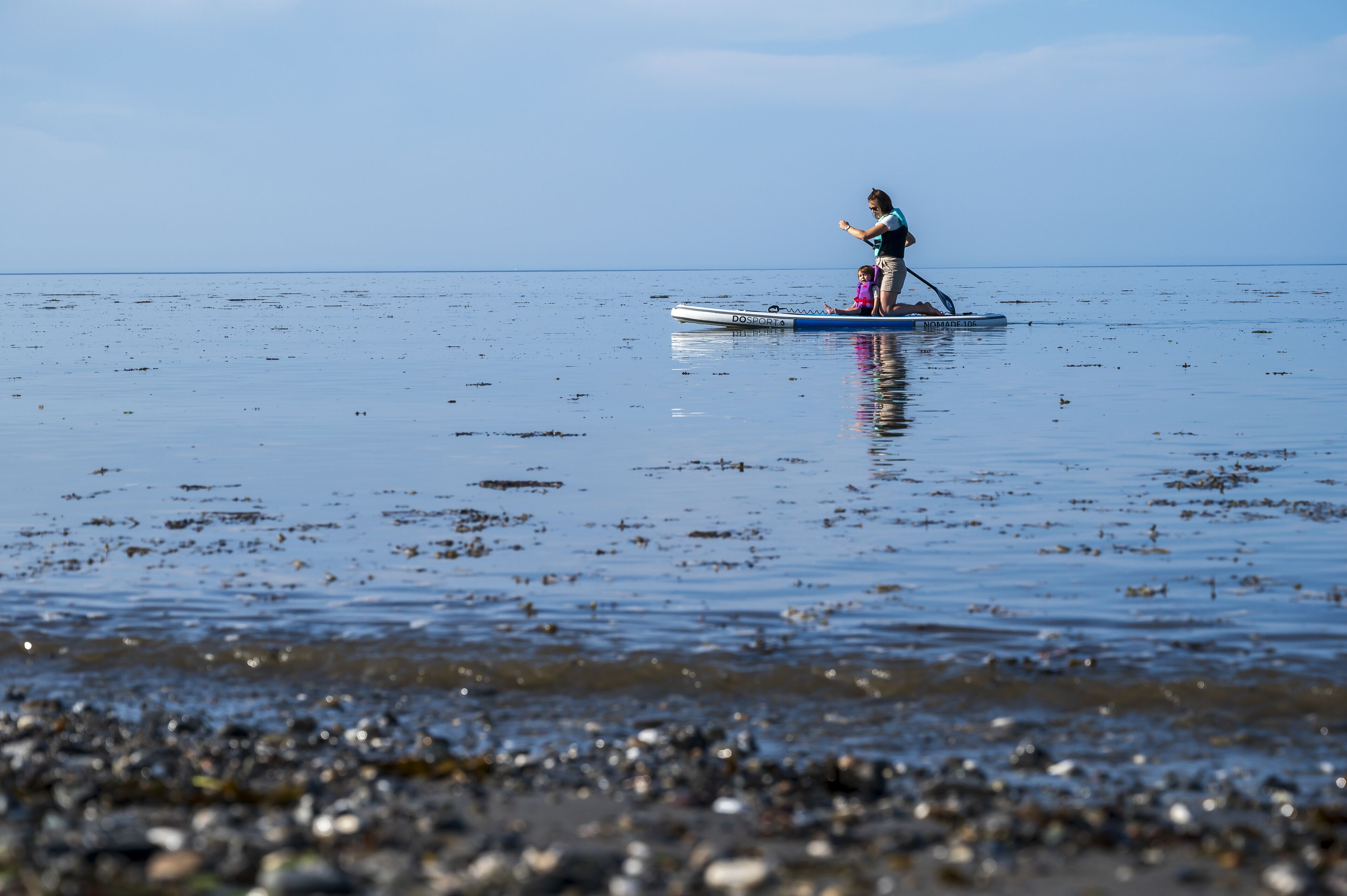 Una persona che fa paddleboard su un'acqua calma con una costa rocciosa.