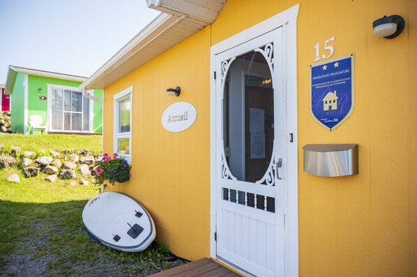 A yellow building with a white door labeled "Accueil" and a plaque indicating "15 Navigateur Village".