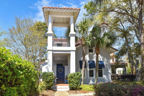 A two-story house with a white facade, a blue door, and a balcony. - Private Home with Carriage House in Exclusive Gated Caribe Community (Miramar Beach)
