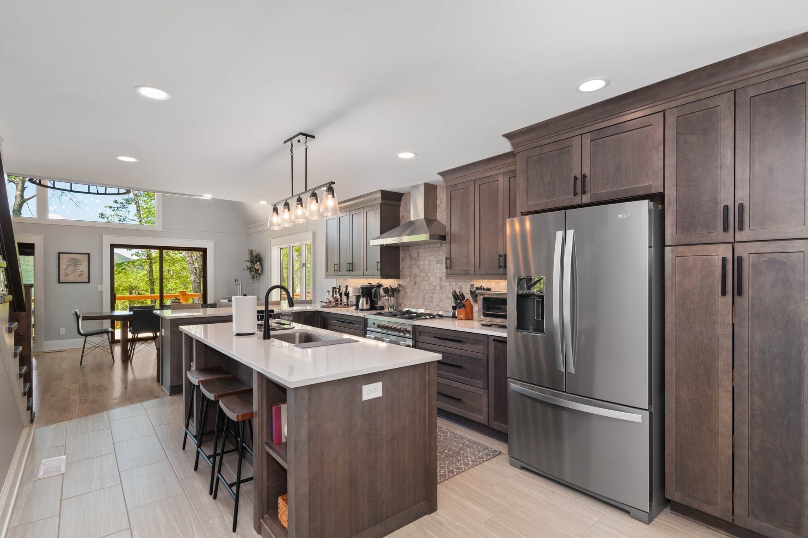 A modern kitchen with dark wood cabinets, stainless steel appliances, and a large island with bar stools.