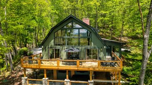 Eine zweistöckige Holzhütte mit Balkon, umgeben von einem Wald.