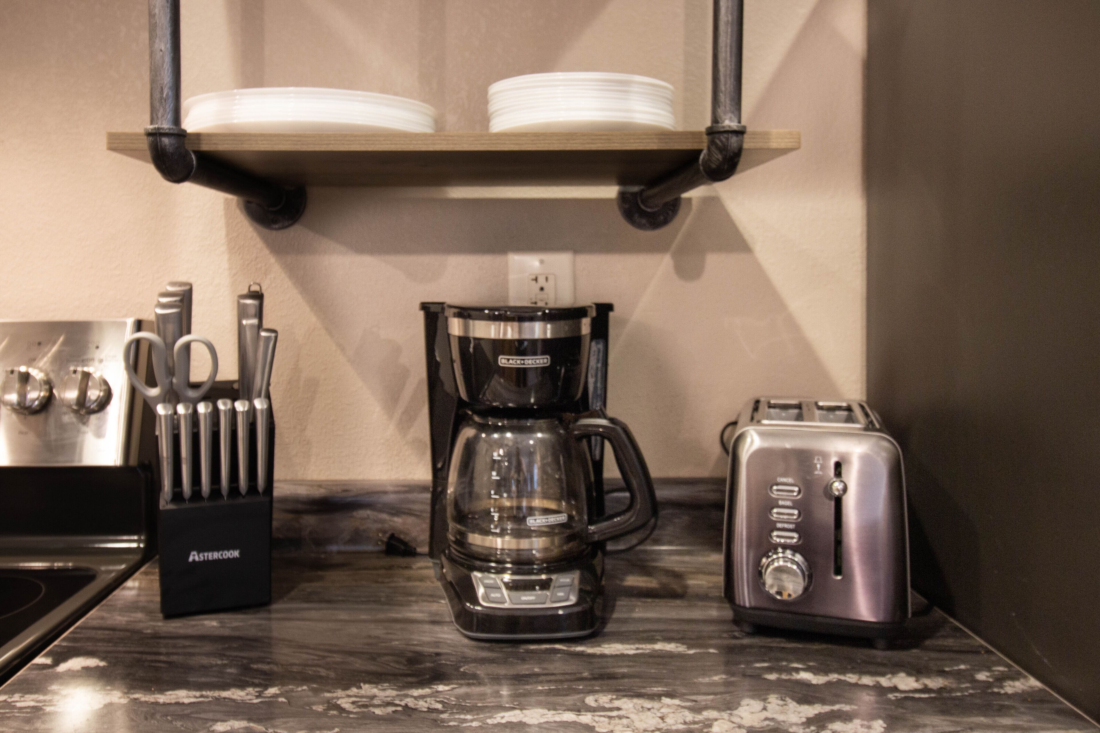 En køkkenbordplade med kaffemaskine, brødrister og et knivdisplay.
