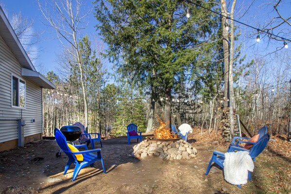 A backyard with a fire pit, blue chairs, and a house. - Remodeled Cabin w/fireplace, 2 miles from Lakewood (Mountain)