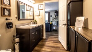 A modern bathroom with a large mirror, dark cabinetry, and a vanity with a sink. - Remodeled Cabin w/fireplace, 2 miles from Lakewood (Mountain)