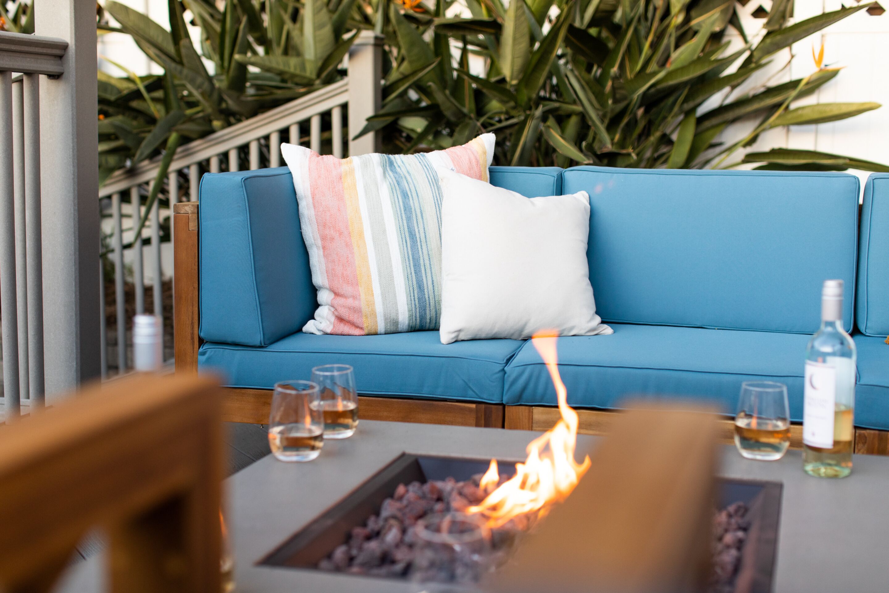 Ein blaues Sofa mit gestreiften Kissen, eine kleine Feuerstelle und zwei Weingläser auf einem Tisch.