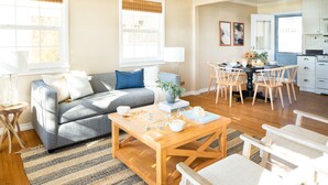 A modern living room with a sofa, coffee table, and dining area.