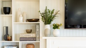 A living room with a fireplace, shelves with books and decorative items, and a television.
