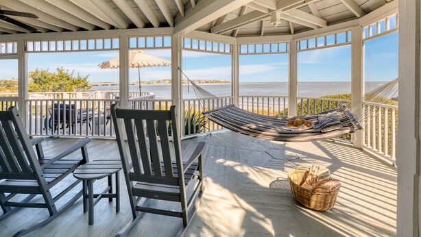 A covered outdoor seating area with a hammock, chairs, and a view of the ocean. - Haven by AvantStay | Luxury Beachfront Home w/ Pool & Gorgeous Patios (Sullivans Island)